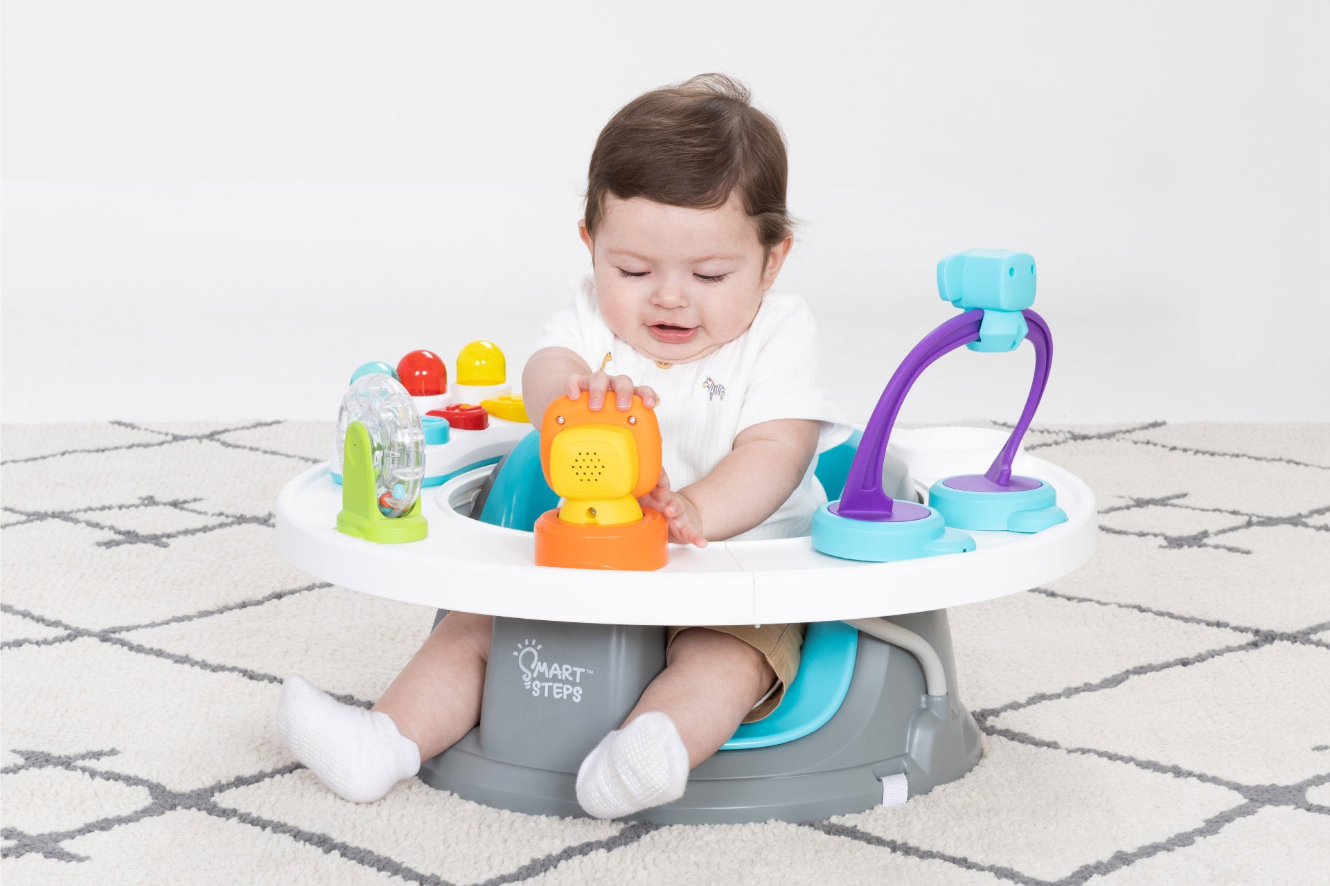A child is sitting in and playing with on the Smart Steps Explore N' Play Activity to Booster Seat